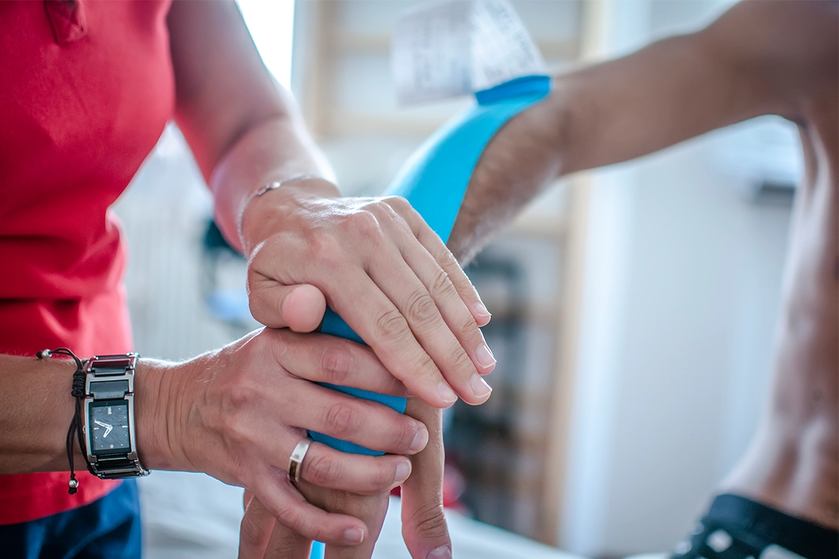 Krankengymnastik-Dresden Neustadt – Therapeut taped Handgelenk zur Stabilisierung und Schmerztherapie